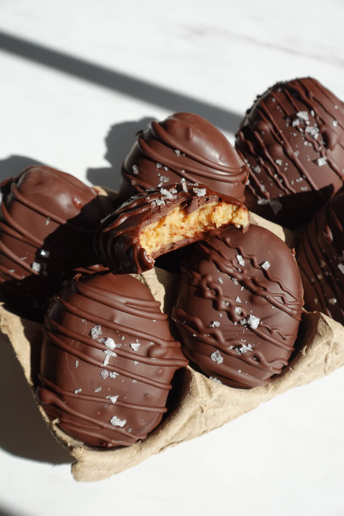 vegan chocolate peanut butter eggs with a bite taken out showing the soft, creamy center