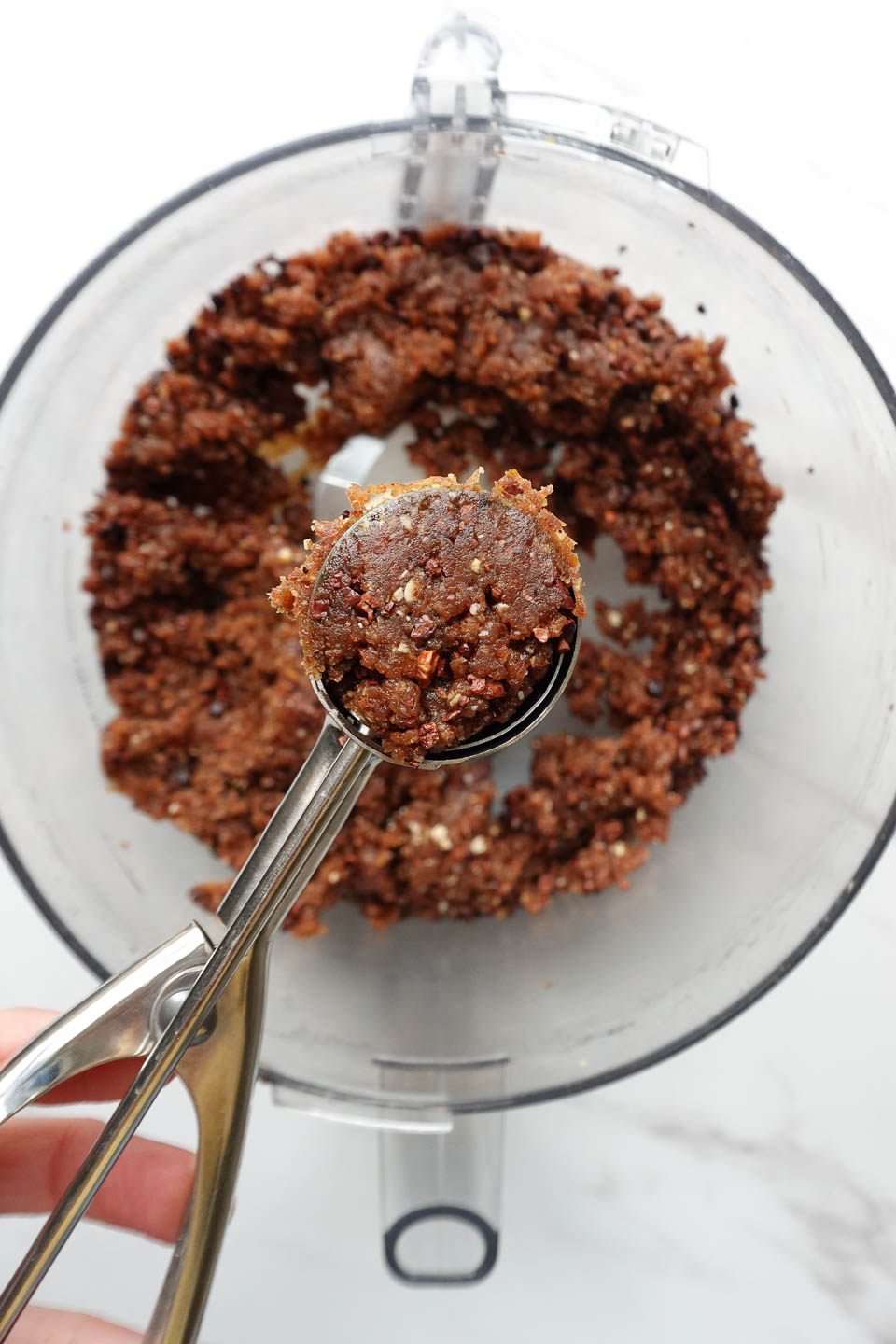 Scooping peanut butter date energy ball mixture into bite-sized portions with a mini cookie scoop