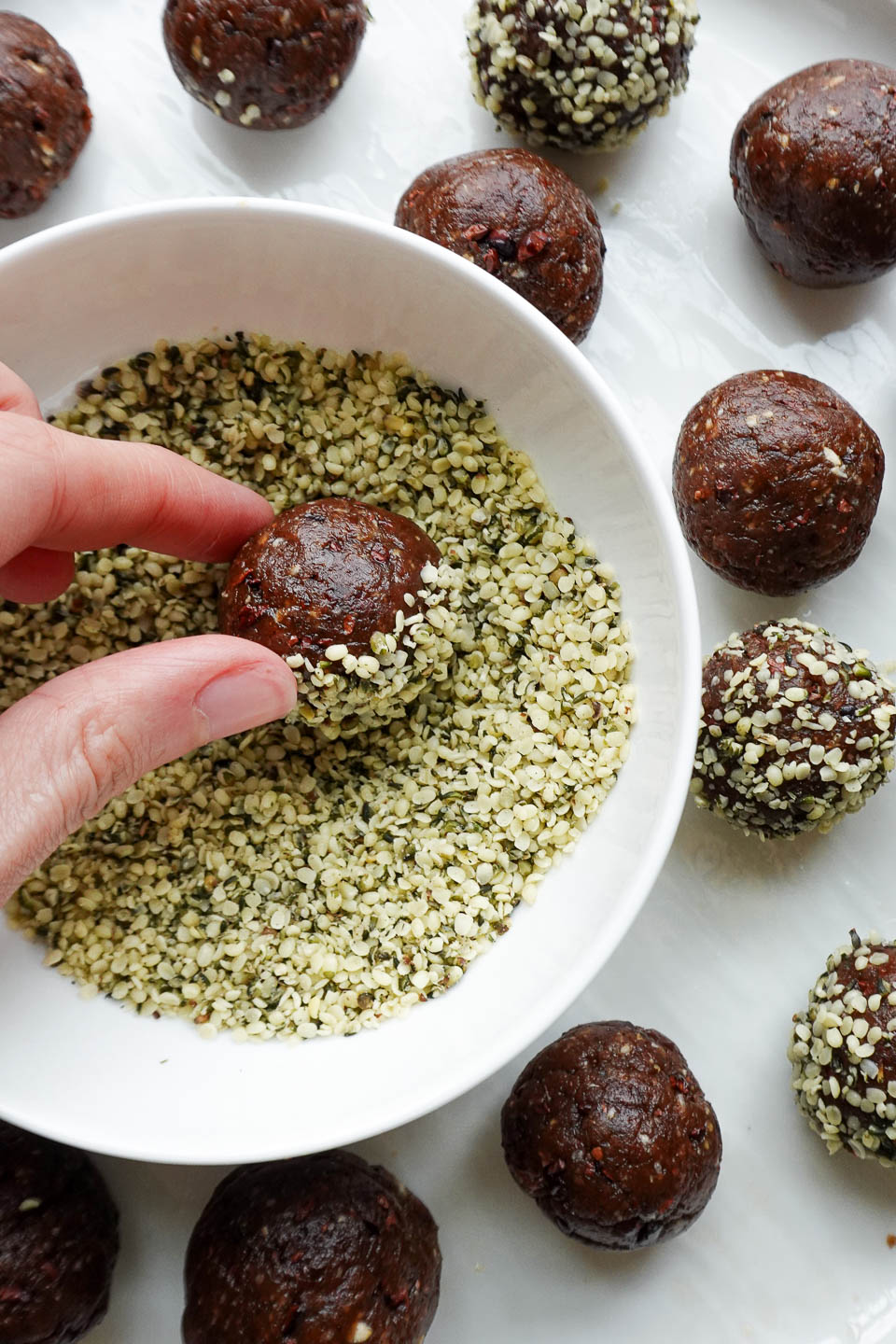 Rolling peanut butter date energy balls in hemp seeds for added texture and plant-based protein