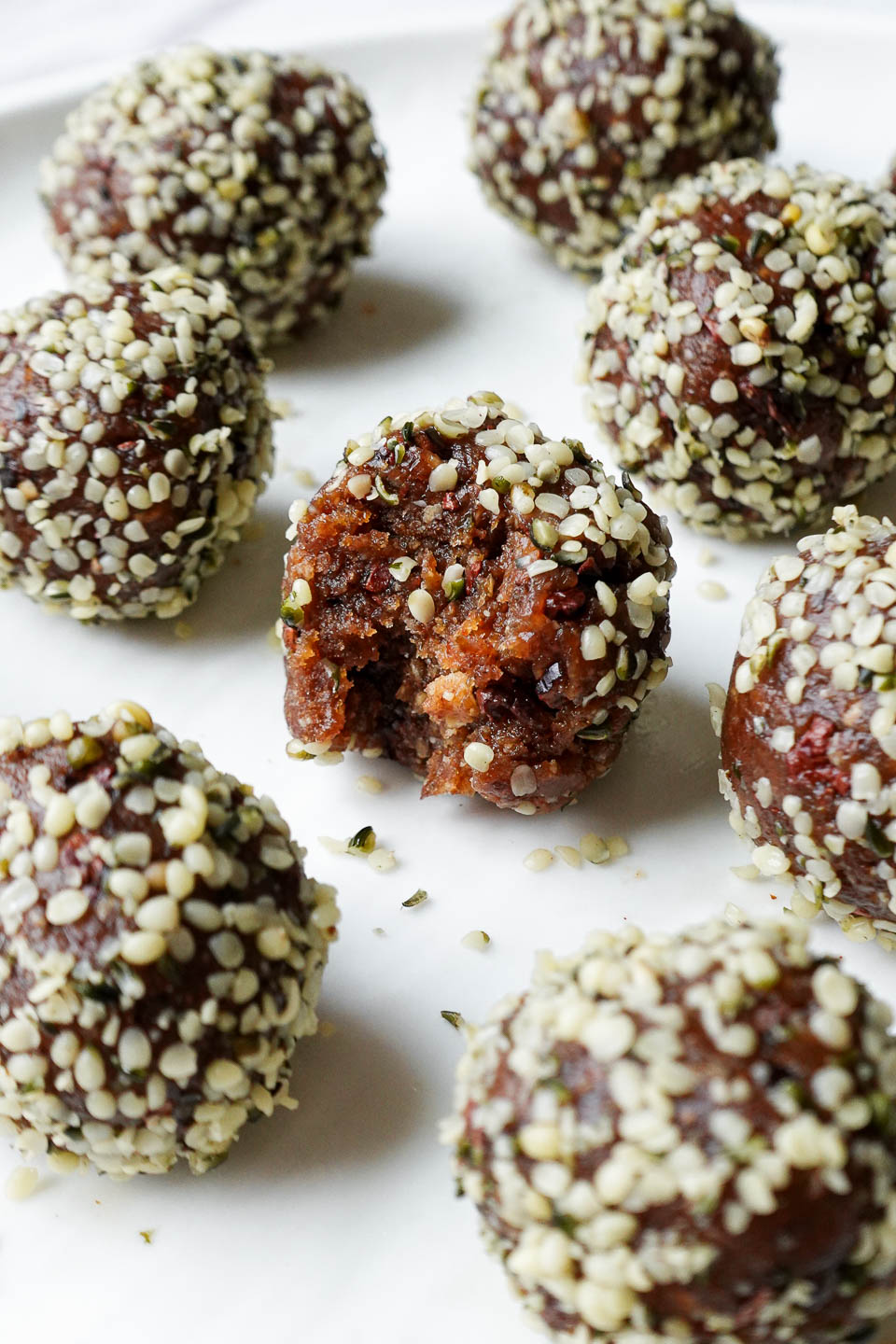 close up of peanut butter energy balls rolled in hemp seeds with a bite taken out, showing it's chewy interior