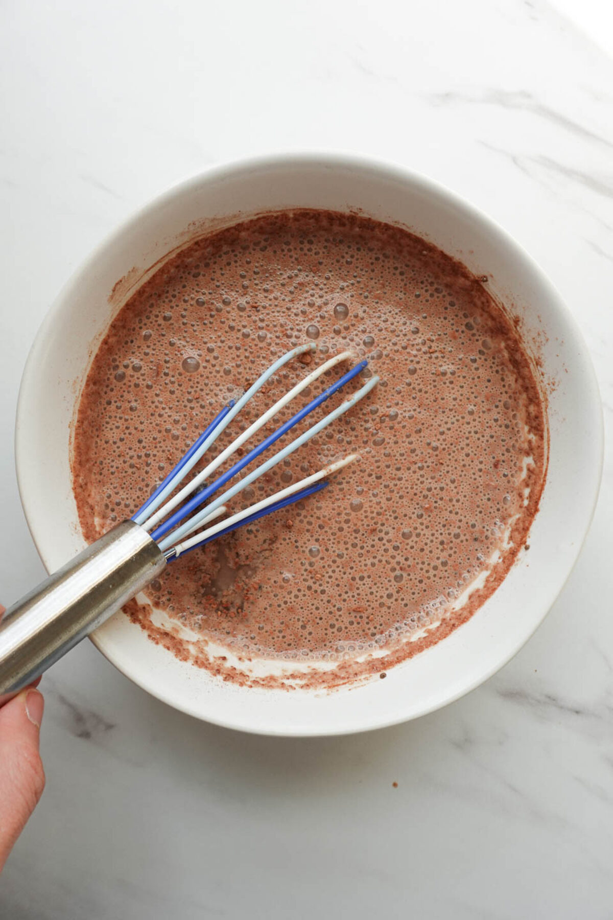whisking chia seeds, cocoa powder, maple syrup, vanilla extract, and non-dairy milk to make chocolate chia pudding layer