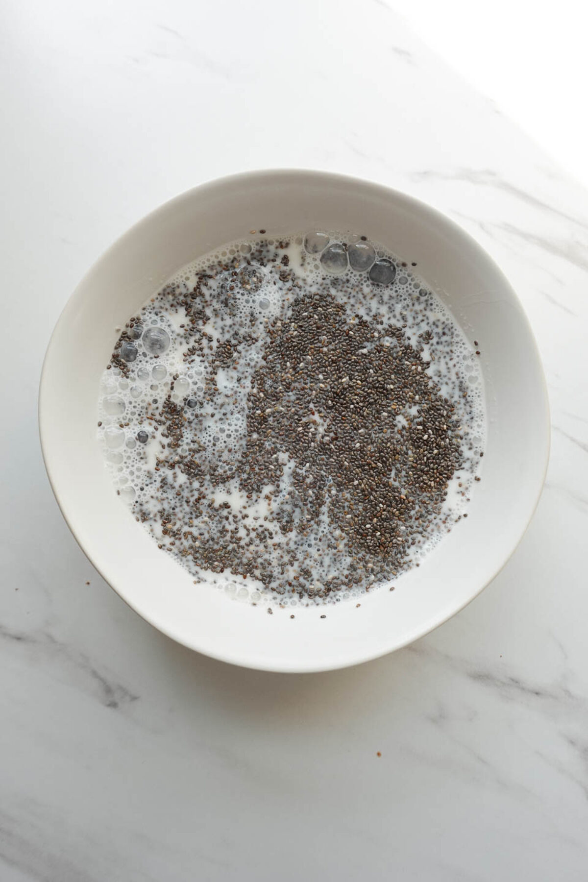 mixing chia seeds, peanut butter, maple syrup, vanilla extract, and non-dairy milk to make peanut butter chia pudding layer