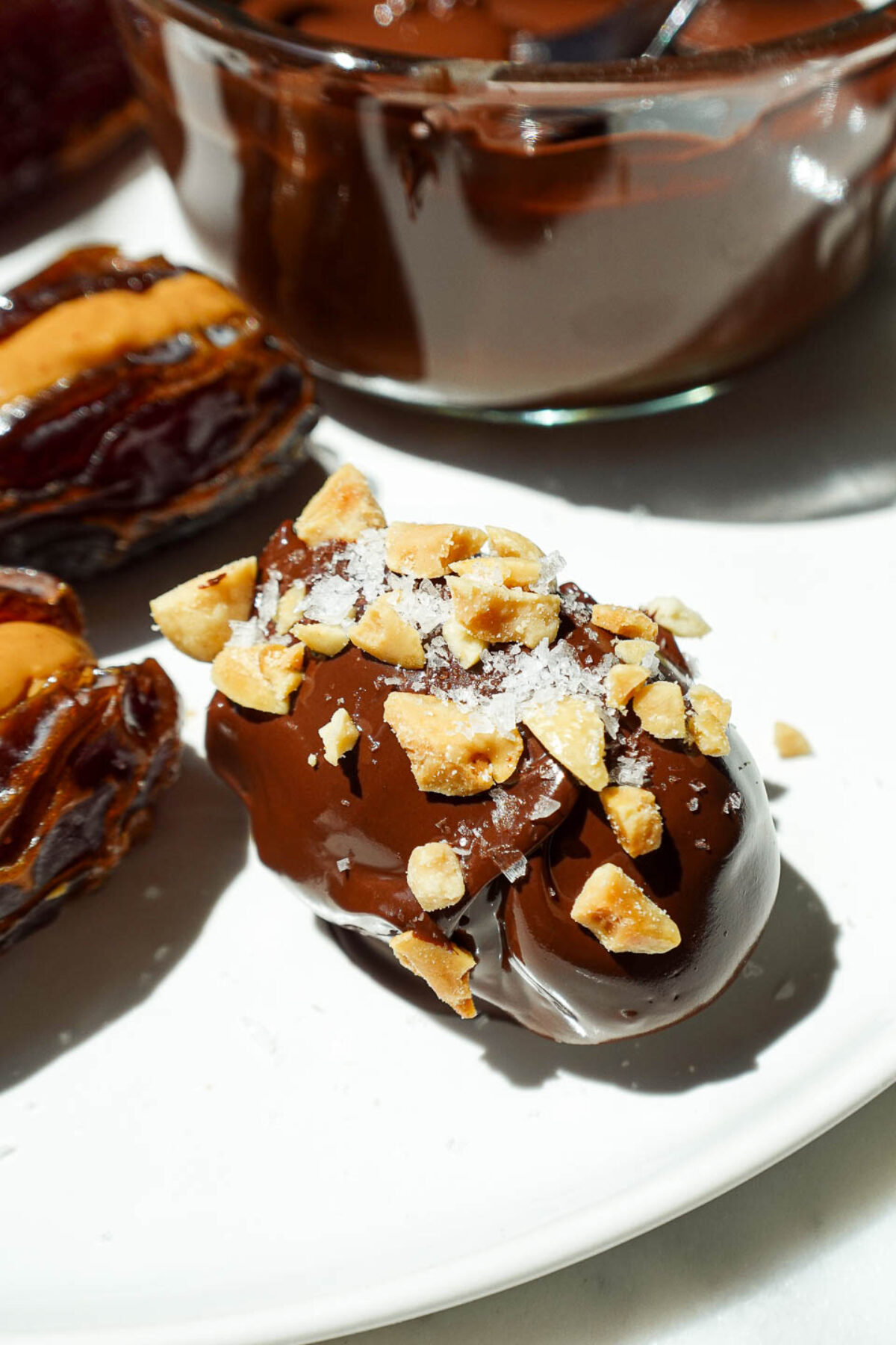 Peanut butter stuffed dates after being dipped in chocolate and sprinkled with chopped peanuts and flaky sea salt.
