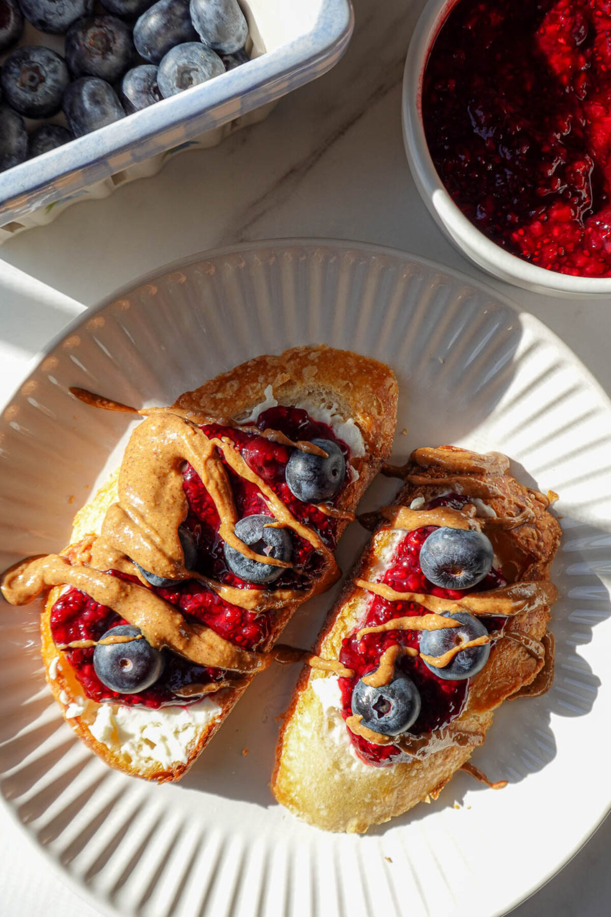 chia jam spread on sourdough with vegan cream cheese, almond butter, and blueberries.
