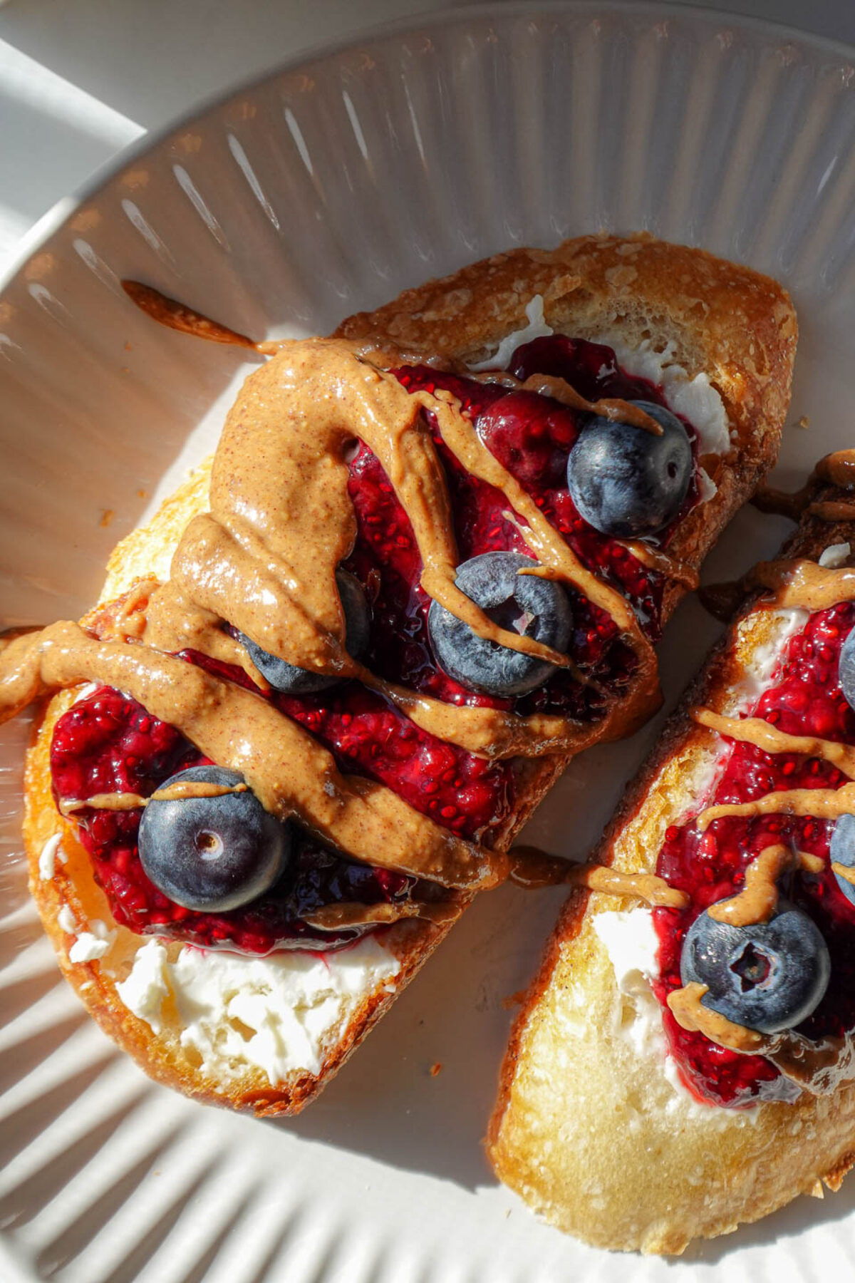 chia jam spread on sourdough with vegan cream cheese, almond butter, and blueberries.