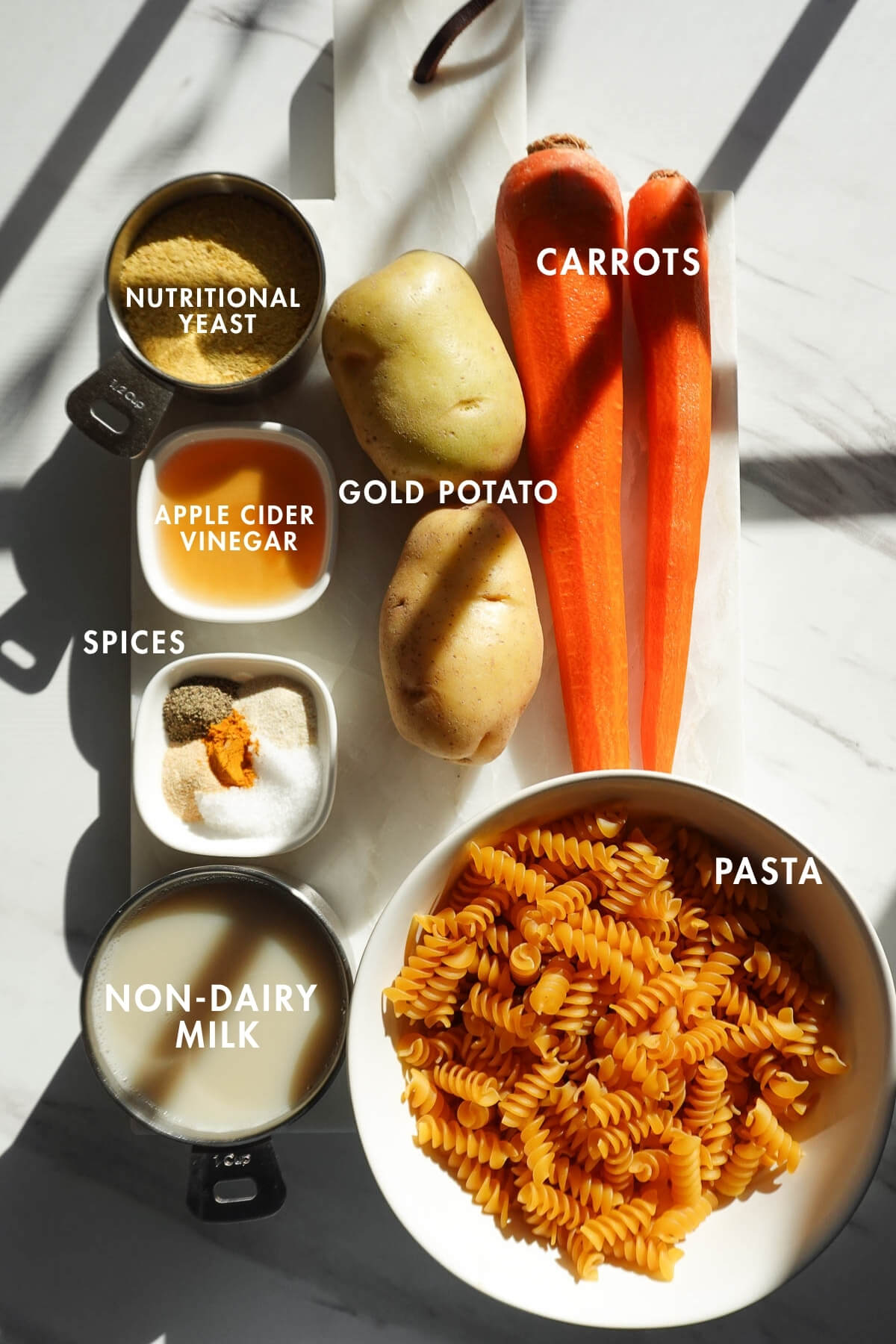 Measured ingredients needed to make vegan mac and cheese on a marble board.