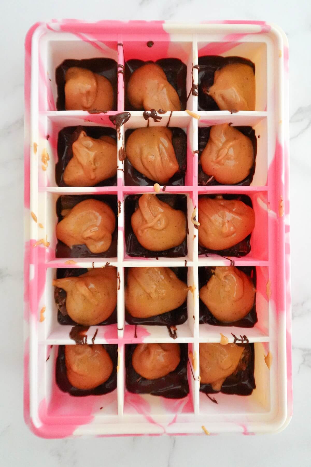 Creamy peanut butter spooned over the Medjool dates inside a silicone mold.
