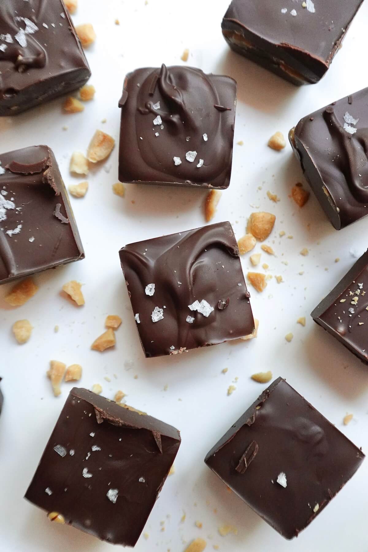Healthy snickers bites sprinkled with flaky sea salt on a white plate.