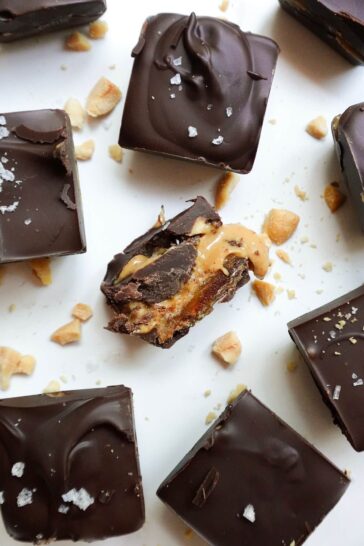 Healthy snickers bites on a white plate with one cut open showing it's gooey interior.