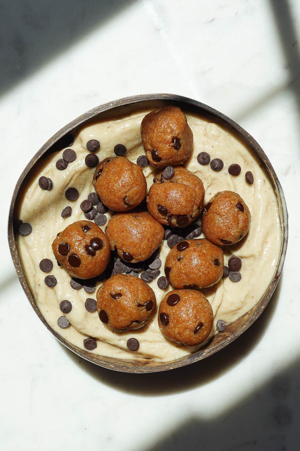 Vegan cookie dough nice cream served in a bowl with chocolate chips and cookie dough pieces on top