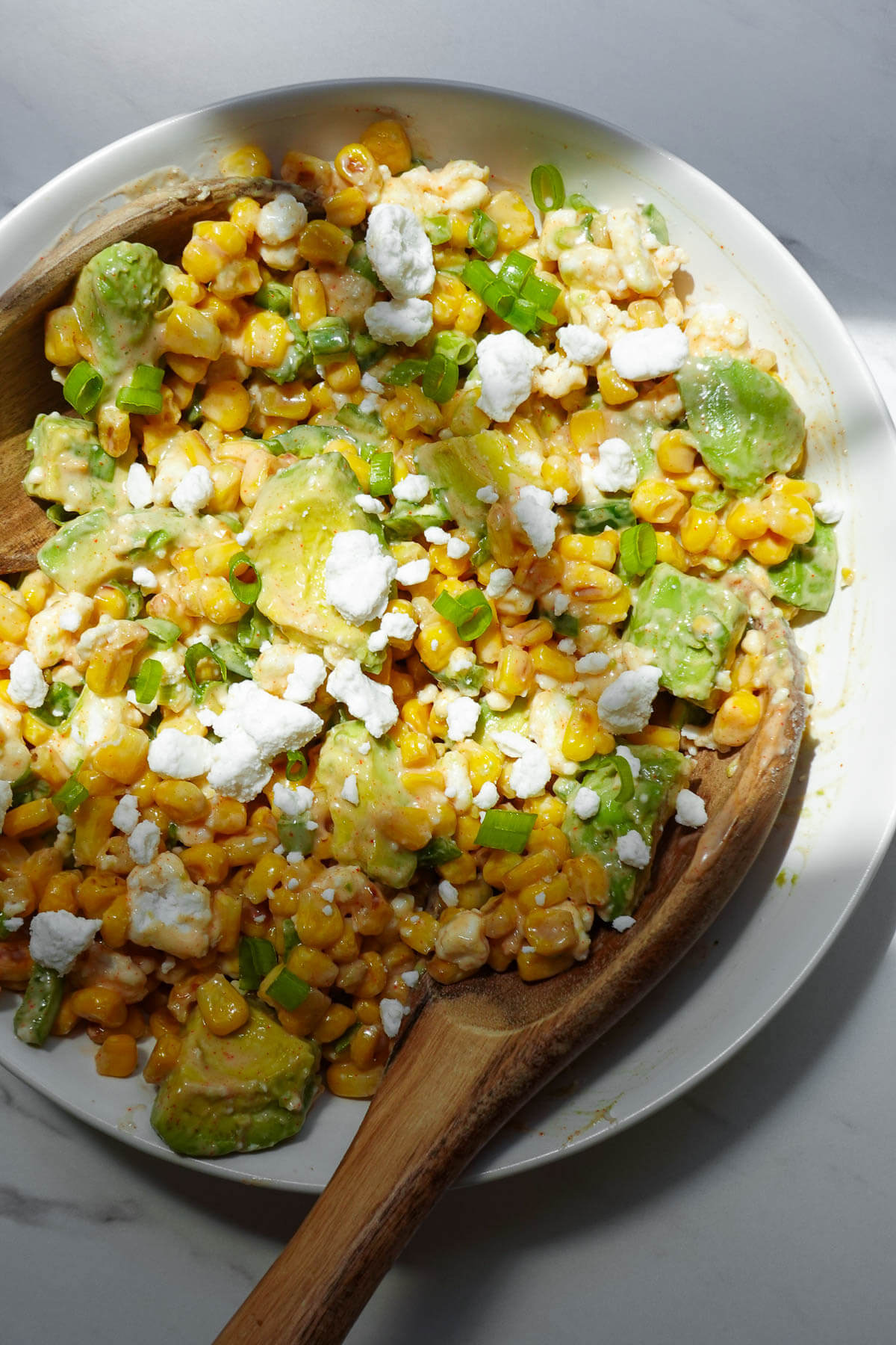 Vegan Mexican street corn salad with avocado, vegan feta, jalapeños, and lime.