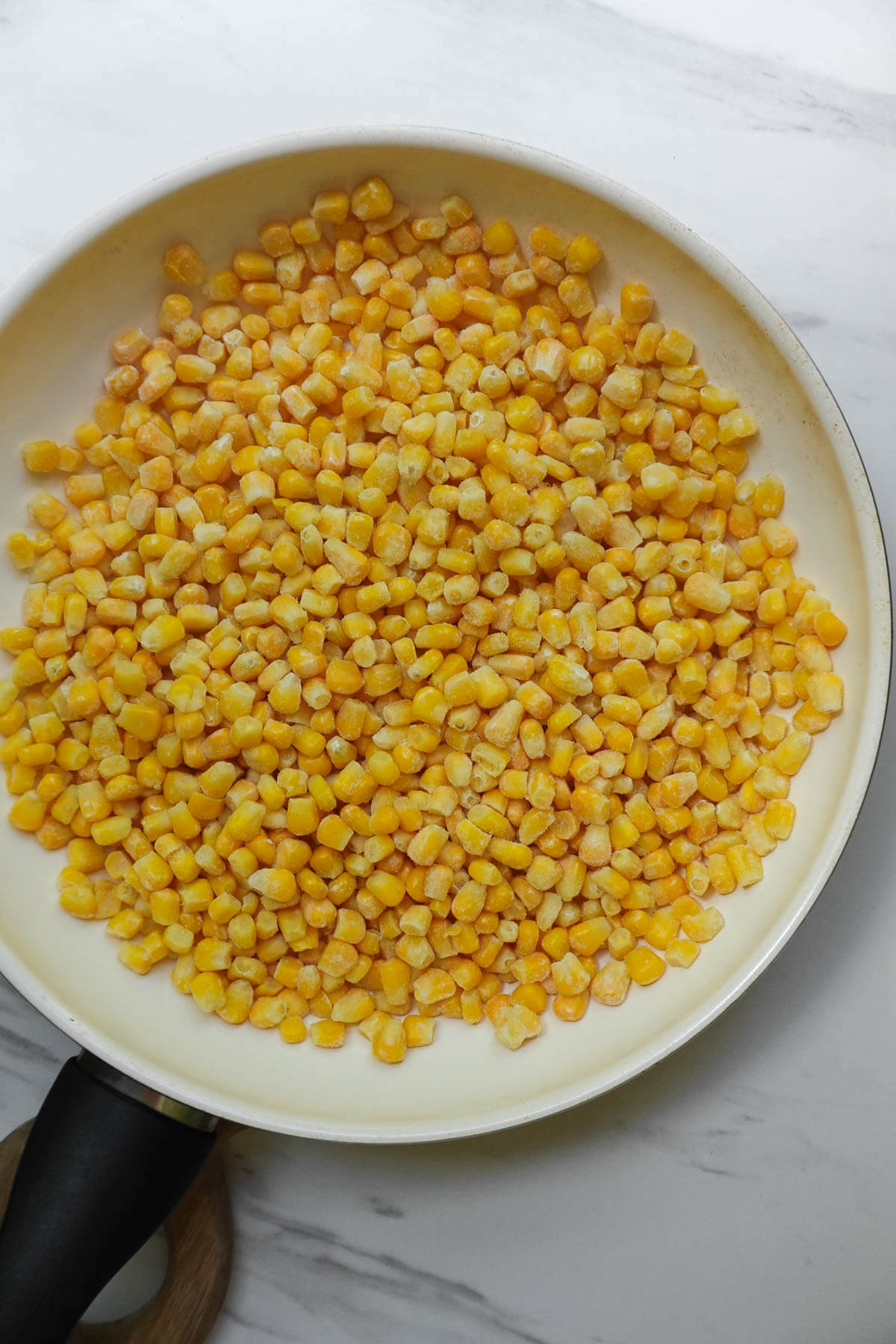 Frozen corn kernels in a skillet.
