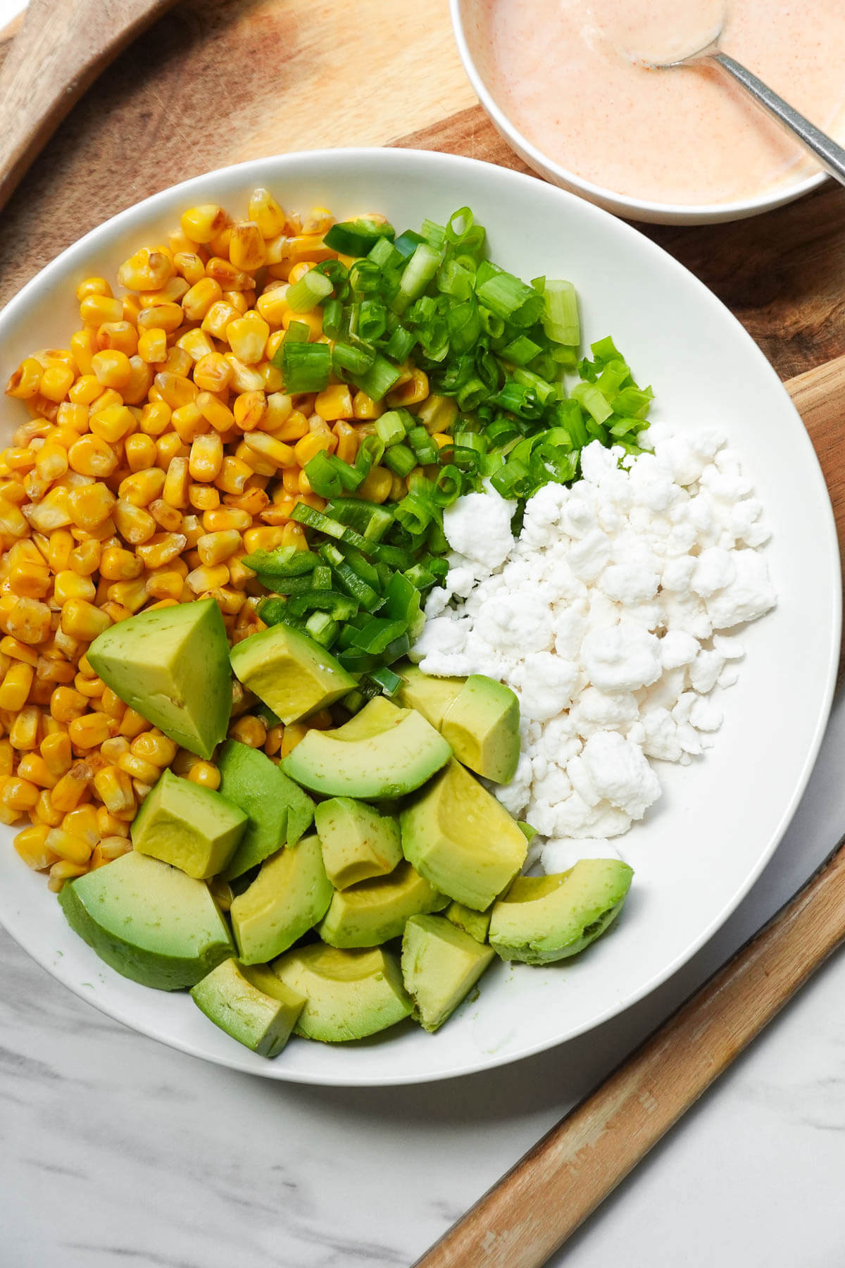 Prepared ingredients for vegan Mexican street corn salad arranged in a bowl.