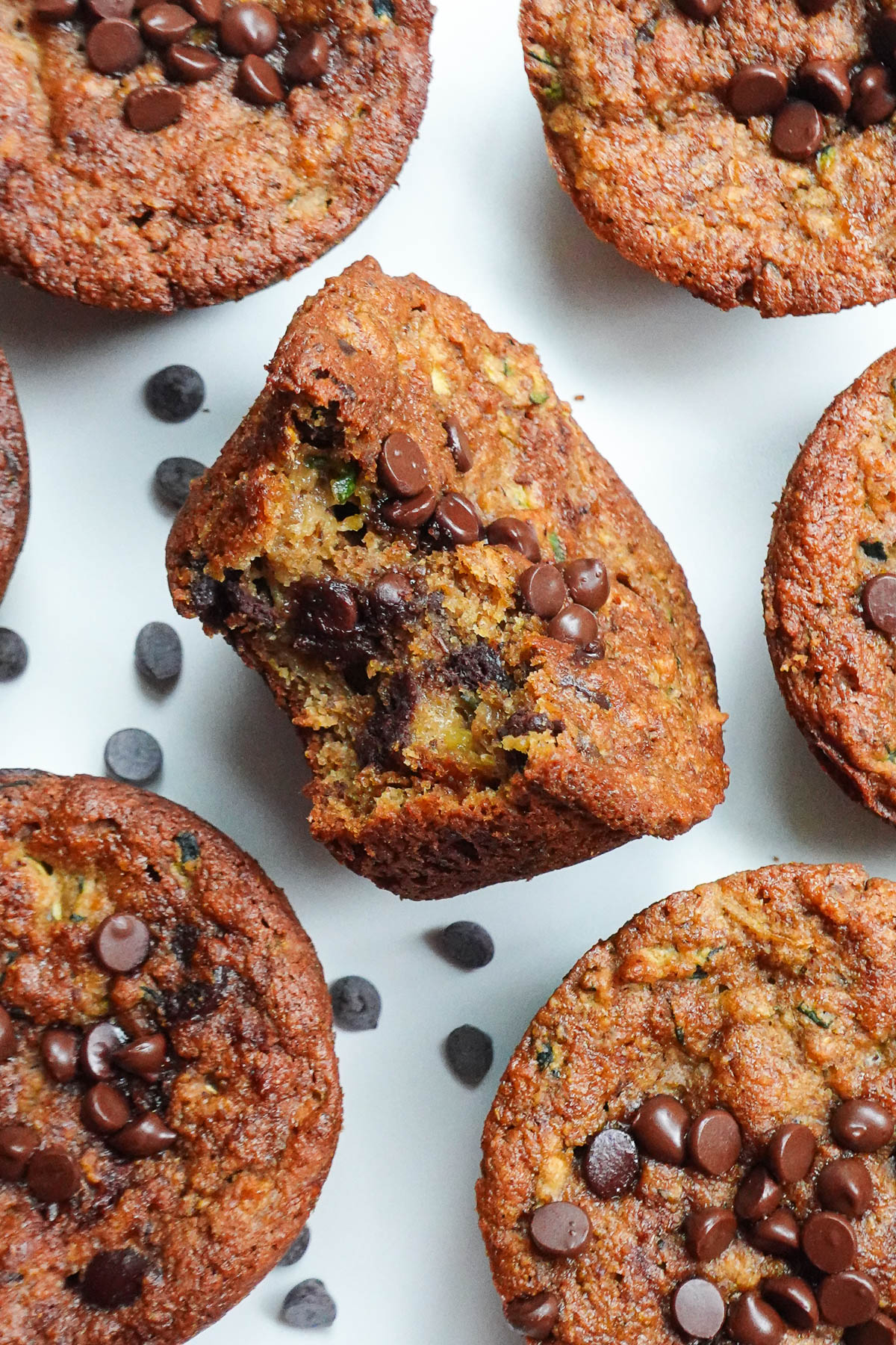 Bite taken out of gluten-free zucchini muffin, showing melted chocolate chips inside.