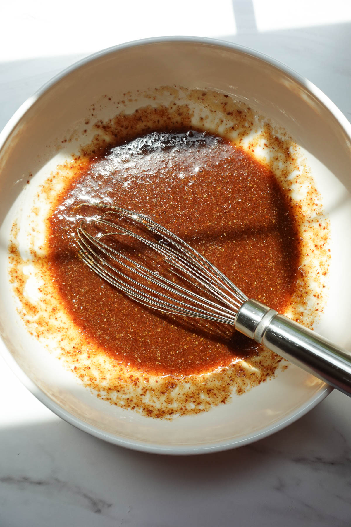 Whisking applesauce, maple syrup, and flax egg for zucchini muffins.