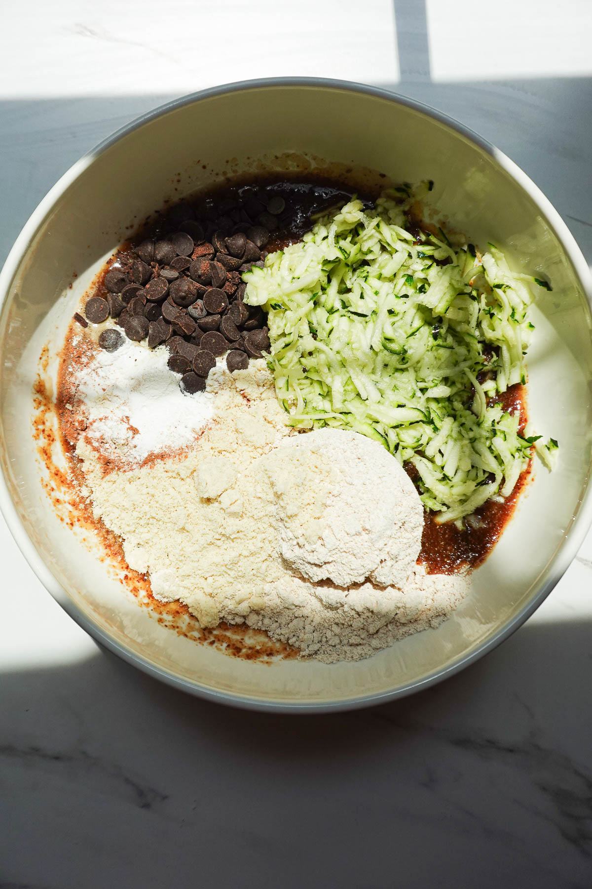 Adding dry ingredients into zucchini muffin batter.