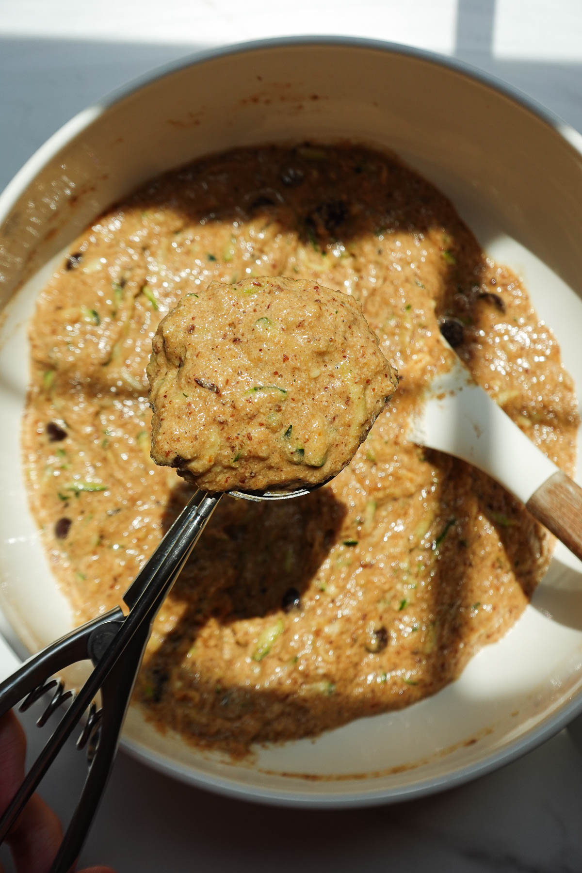 Scooping portions for vegan zucchini muffins.