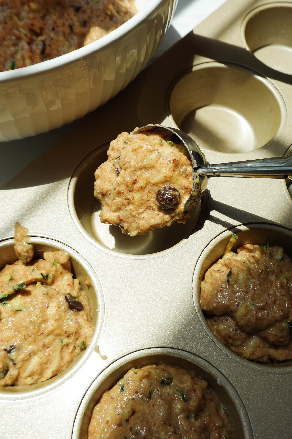 Scooping batter into muffin tin.