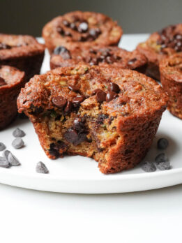 Bite taken out of gluten-free zucchini muffin, showing melted chocolate chips inside.