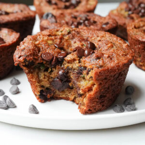 Bite taken out of gluten-free zucchini muffin, showing melted chocolate chips inside.