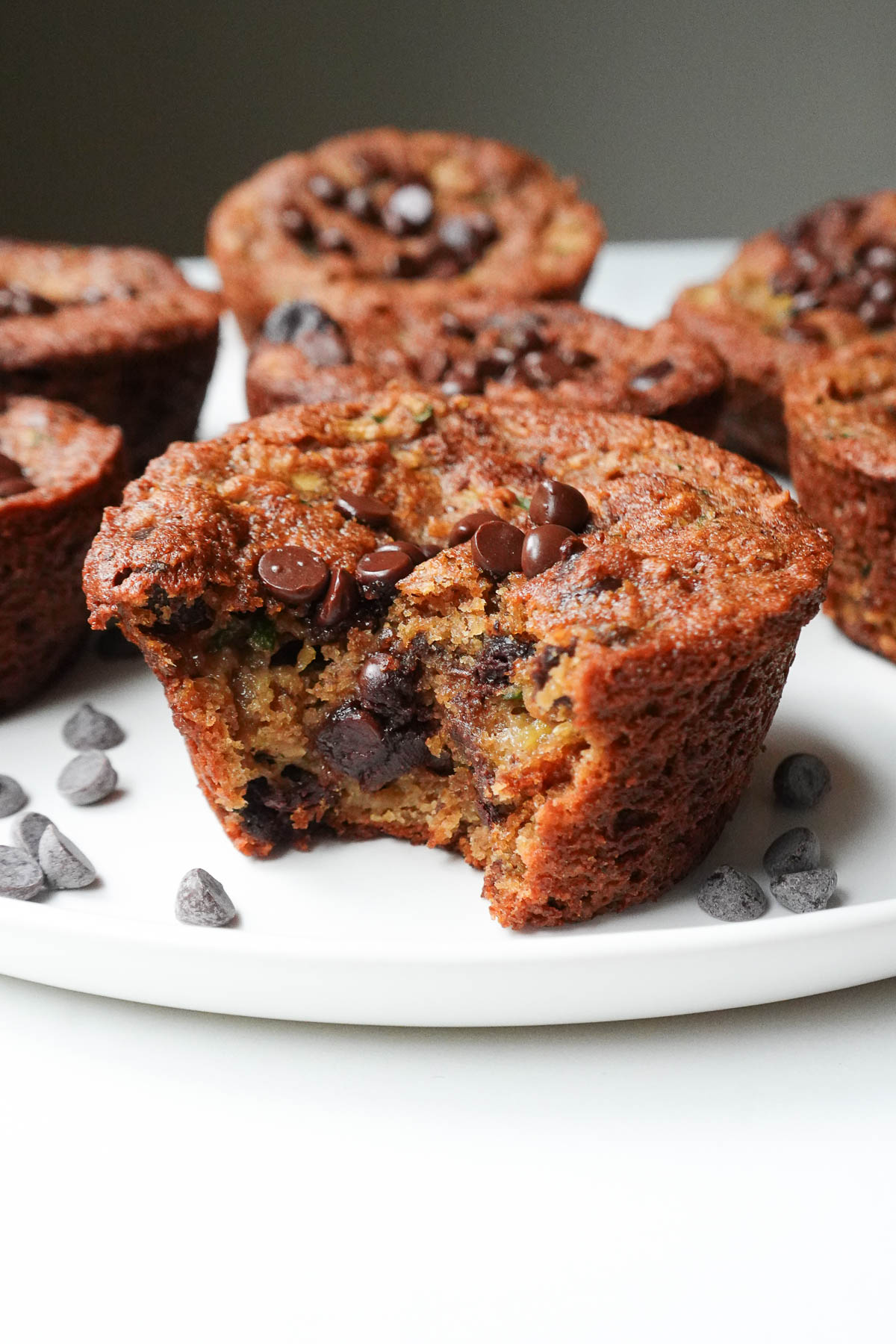 Bite taken out of gluten-free zucchini muffin, showing melted chocolate chips inside.