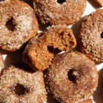 Baked apple cider donuts coated in cinnamon sugar on a plate