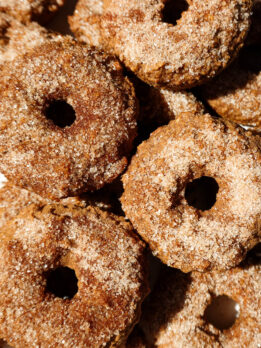 Baked apple cider donuts coated in cinnamon sugar on a plate