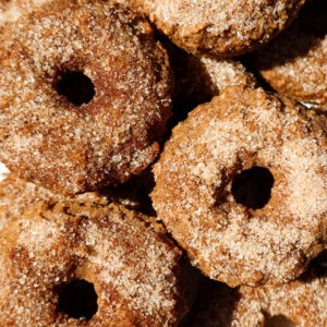 Baked apple cider donuts coated in cinnamon sugar on a plate