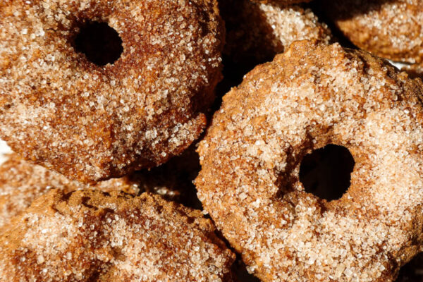 Baked apple cider donuts coated in cinnamon sugar on a plate