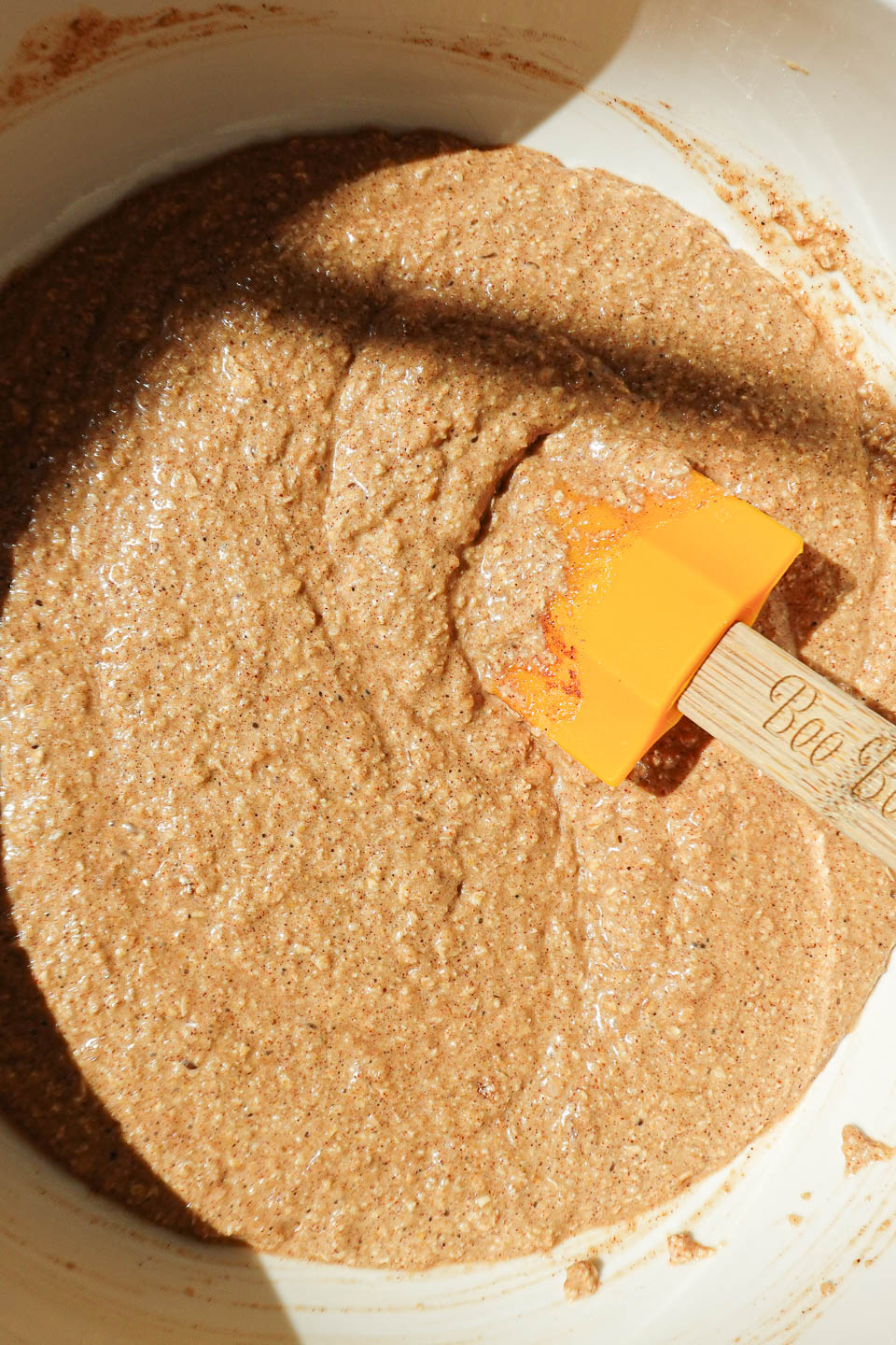 Whisking vegan apple cider donut batter with oat flour and applesauce in a mixing bowl