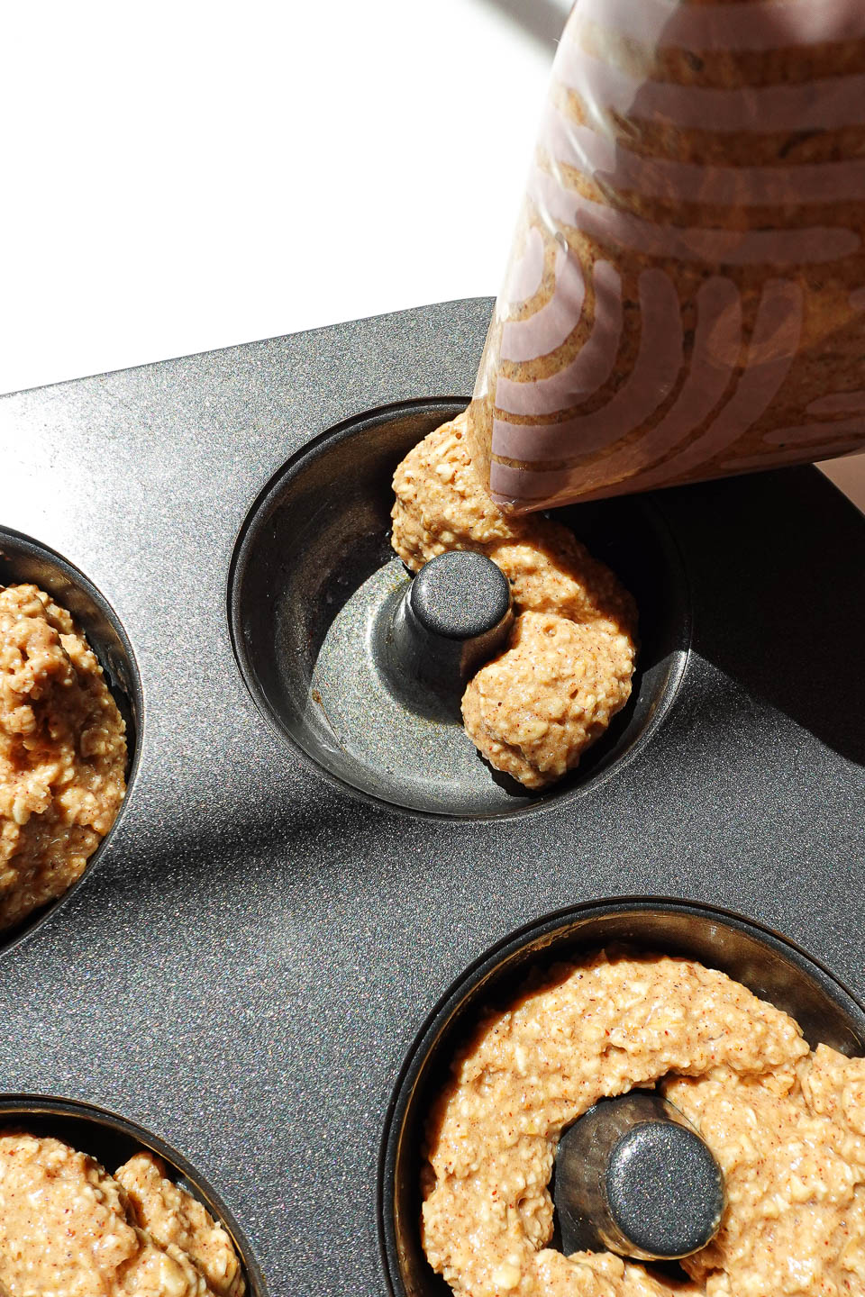 Piping apple cider donut batter into a mini donut pan