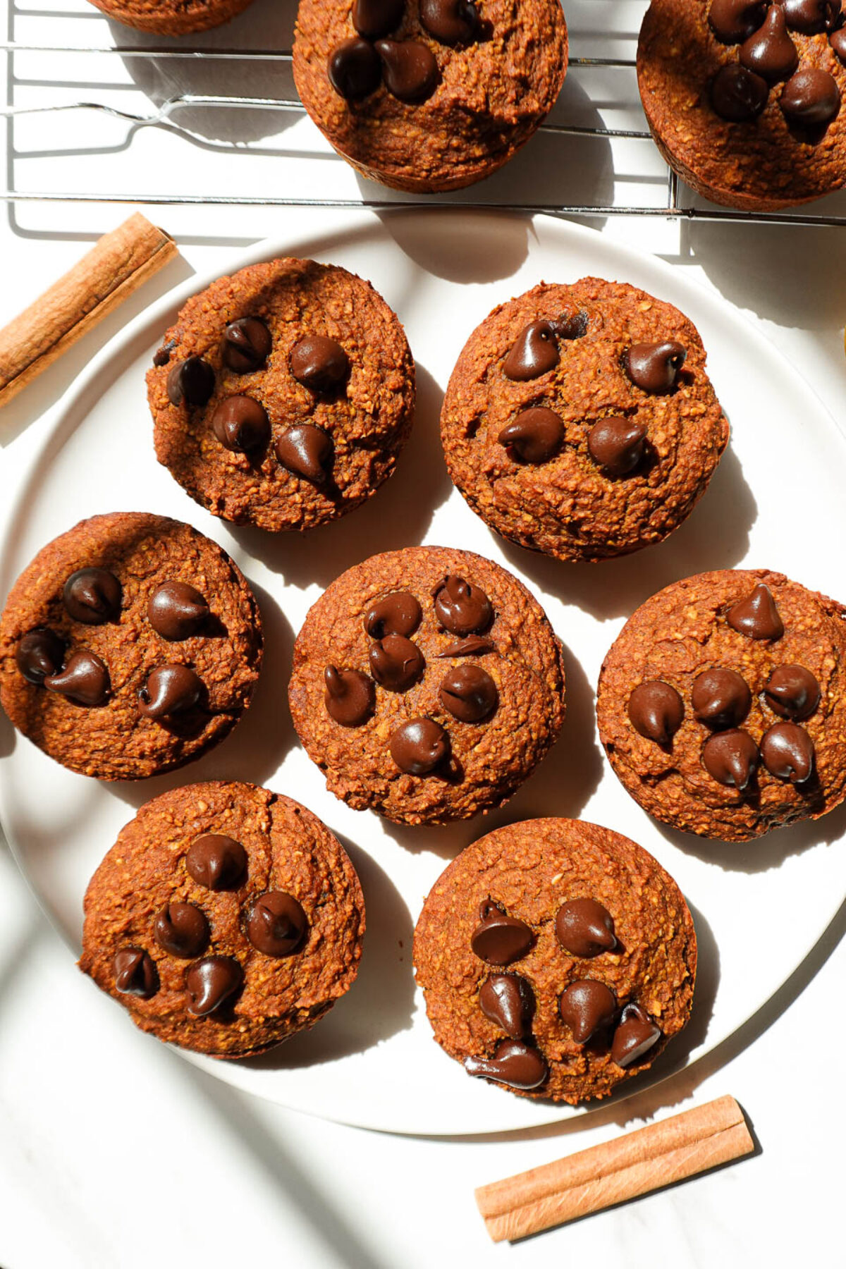 overhead shot of healthy pumpkin muffins on a plate garnished with a cinnamon stick