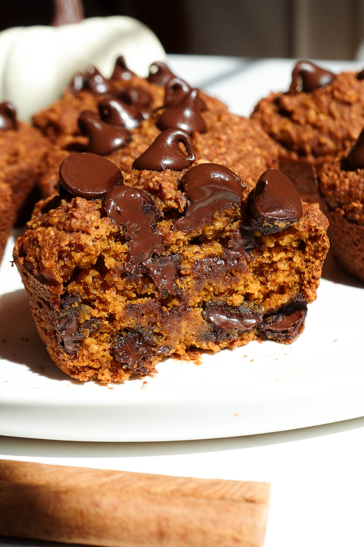 Vegan pumpkin muffin cut in half to show soft crumb and melty chocolate chips.