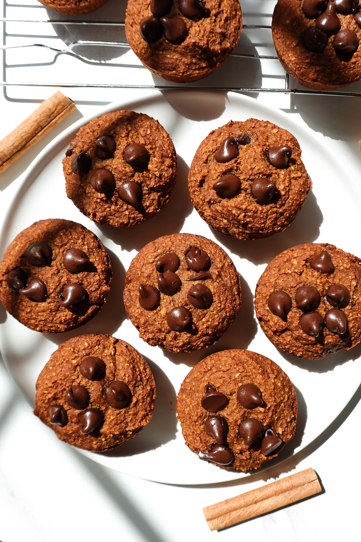 Healthy pumpkin muffins on a plate garnished with a cinnamon stick.