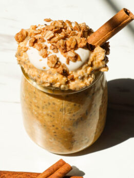 Creamy pumpkin pie overnight oats in a glass jar topped with granola and yogurt