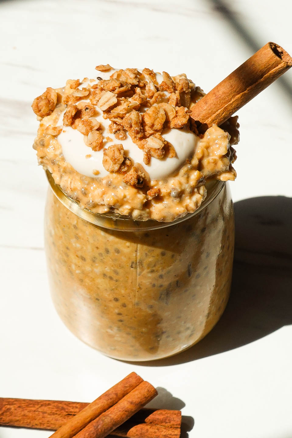 Creamy pumpkin pie overnight oats in a glass jar topped with granola and yogurt