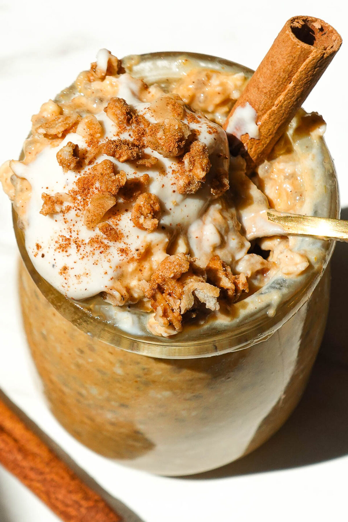 Close up of pumpkin pie overnight oats topped with yogurt, granola, and a sprinkle of cinnamon.