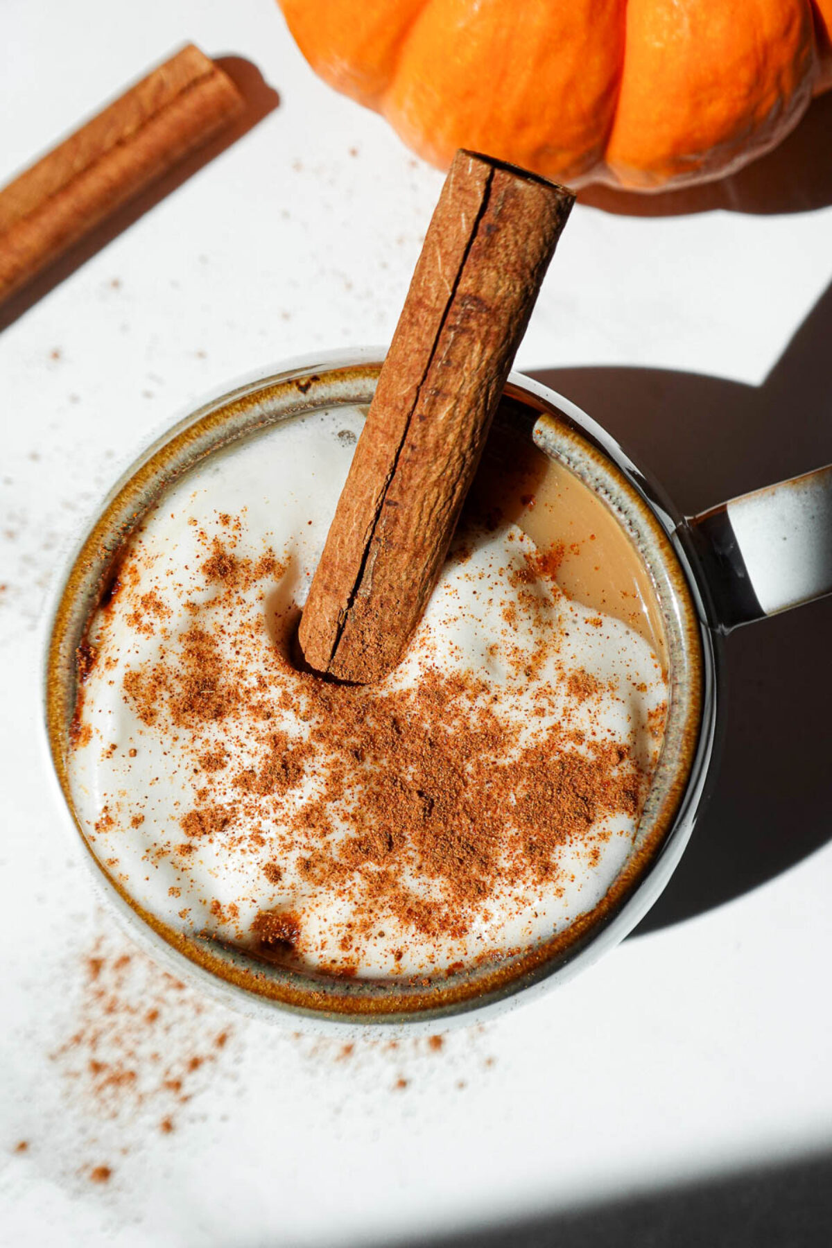 Overhead shot of my pumpkin spice chai tea latte with a cinnamon stick garnish on a fall-themed table setting