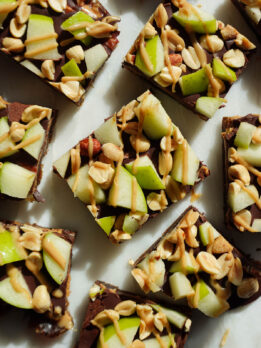 Caramel apple date bark topped with dark chocolate, diced green apple, peanut butter, and chopped peanuts.