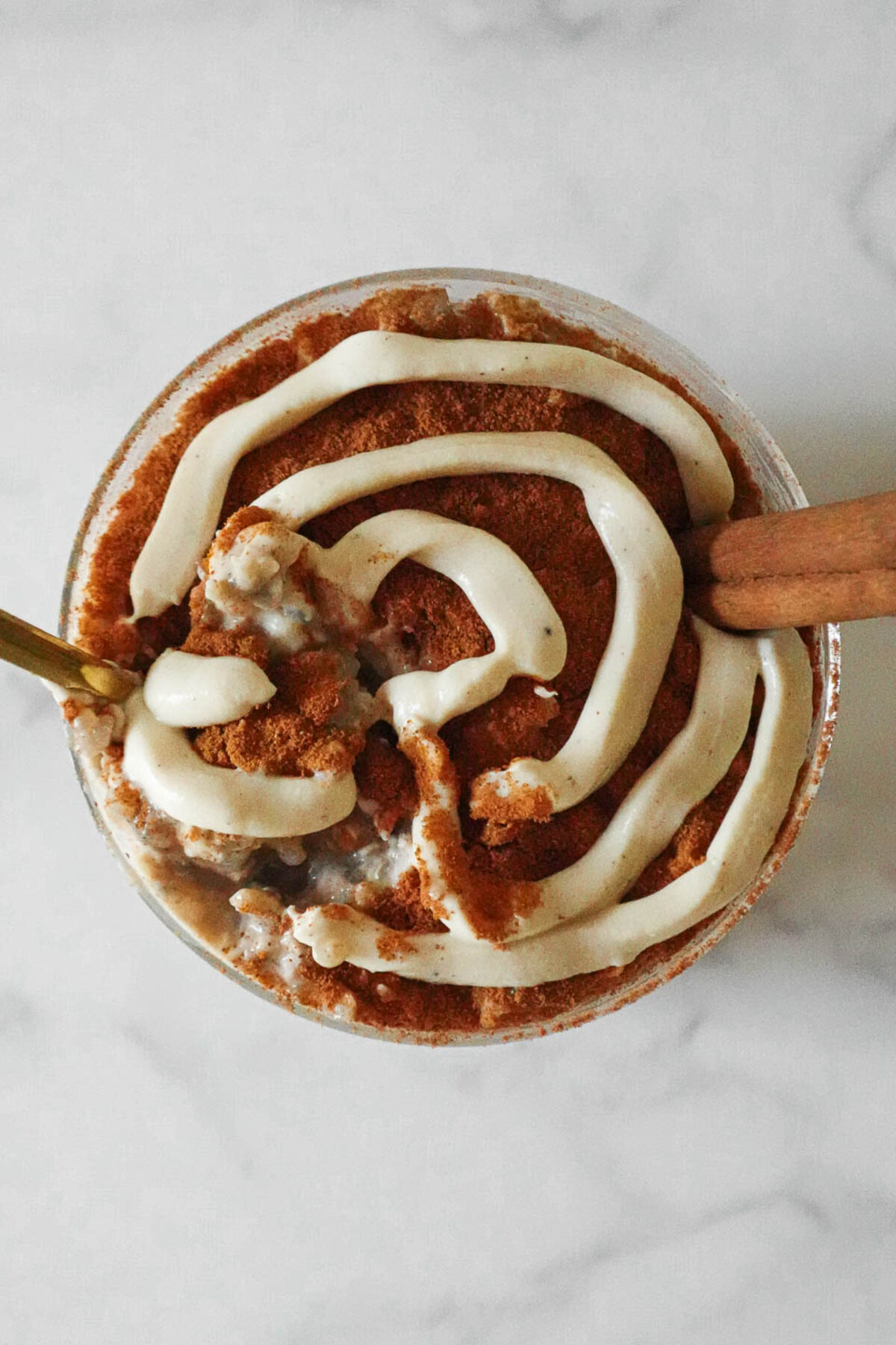 Creamy Cinnamon Roll Overnight Oats with a yogurt swirl and a cinnamon stick and a spoonful