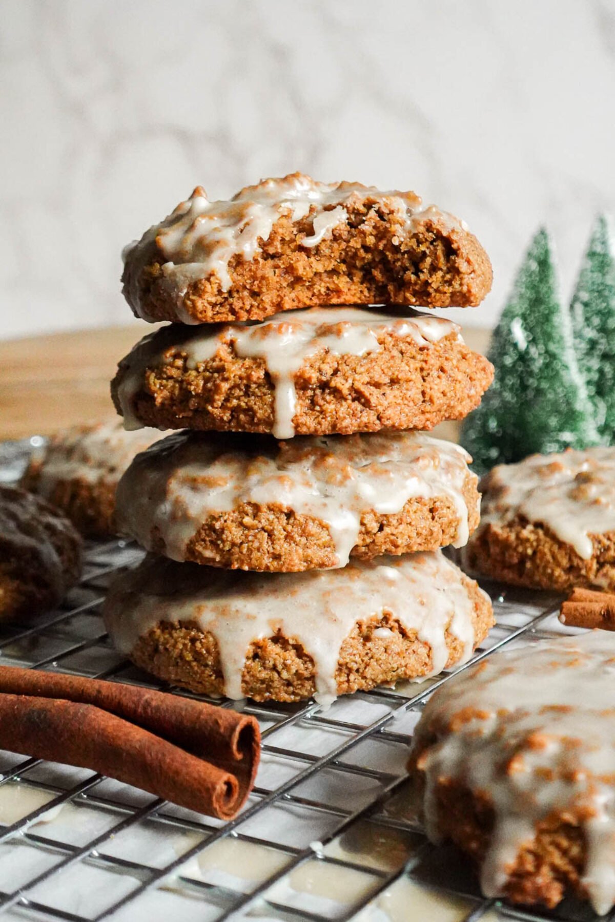 Stack of round, soft iced gingerbread cookies with a bite taken out of the top cookie, showing a fluffy interior.