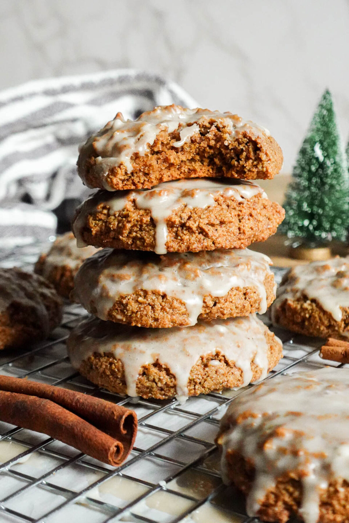 Close-up of stacked soft vegan and gluten-free iced gingerbread cookies with a bite taken out, revealing the light and fluffy texture inside.