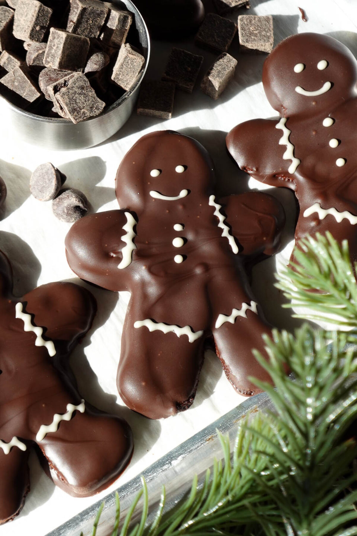 Festive gluten-free vegan chocolate peppermint cookies in gingerbread man shape, decorated with white chocolate and peppermint flavors