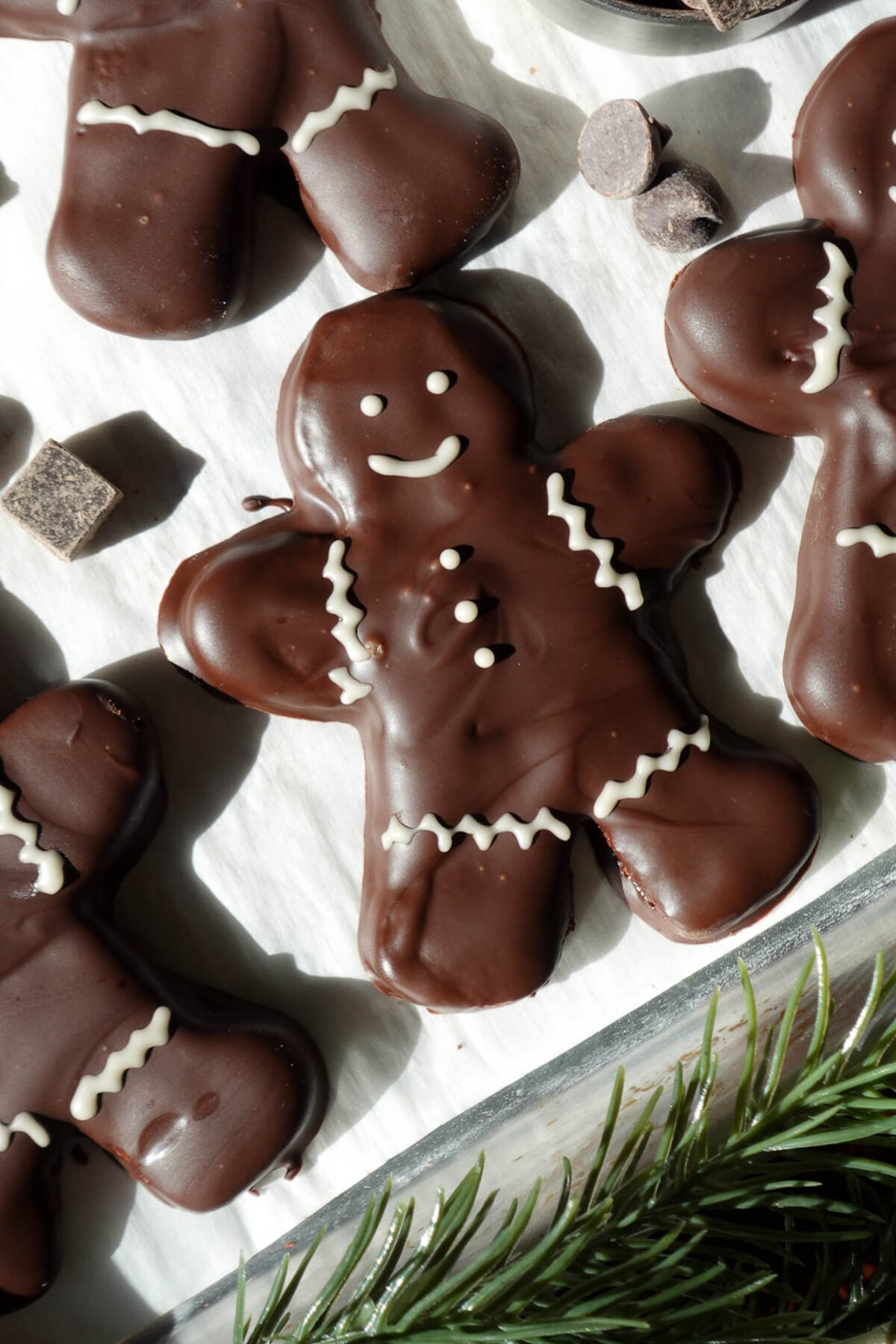 Close-up of vegan chocolate peppermint gingerbread men cookies dipped in melted chocolate and decorated with white chocolate details