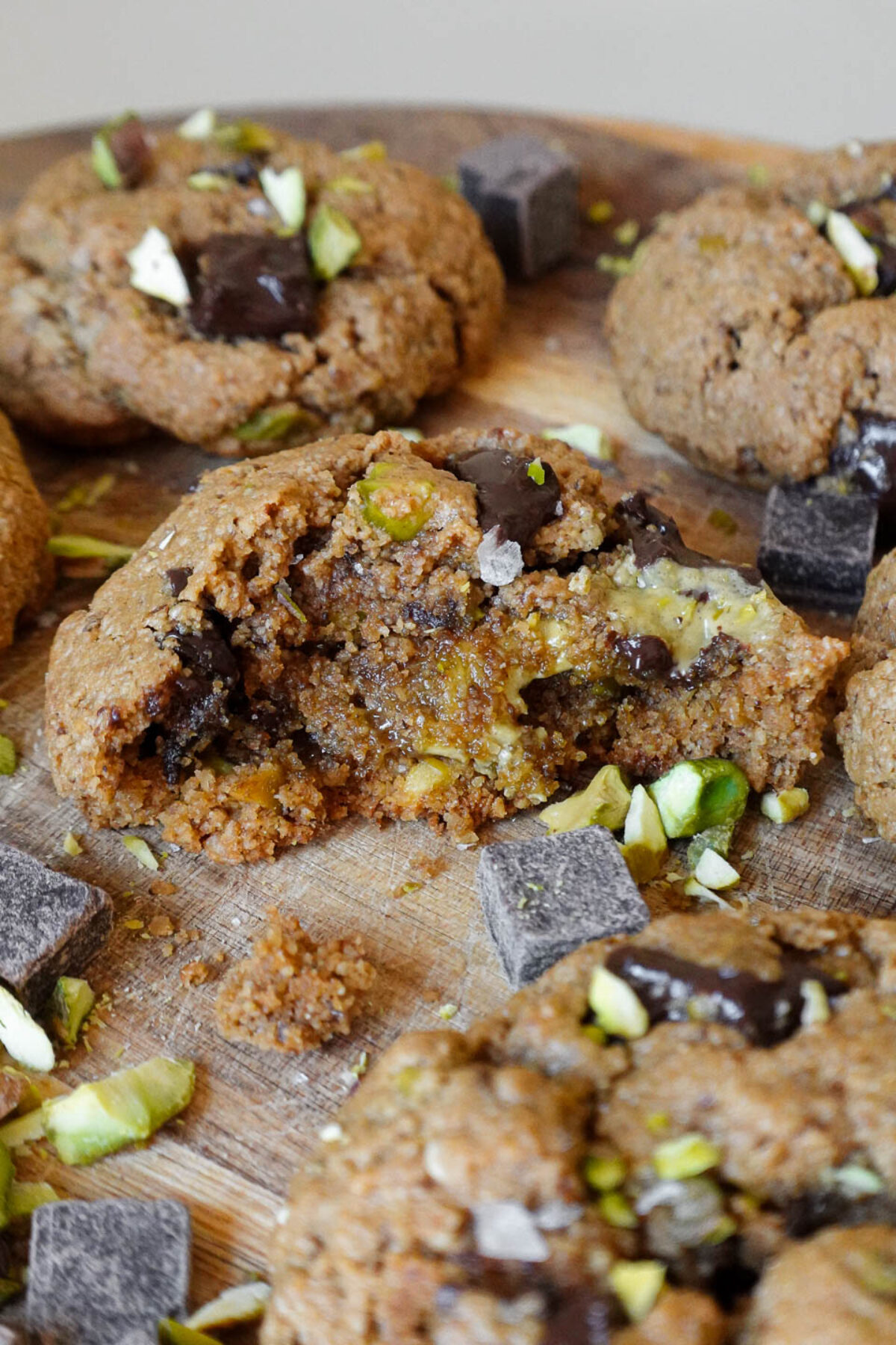 vegan and gluten-free pistachio chocolate chip cookies with a bite taken out of it revealing a soft and chewy center with pistachio butter