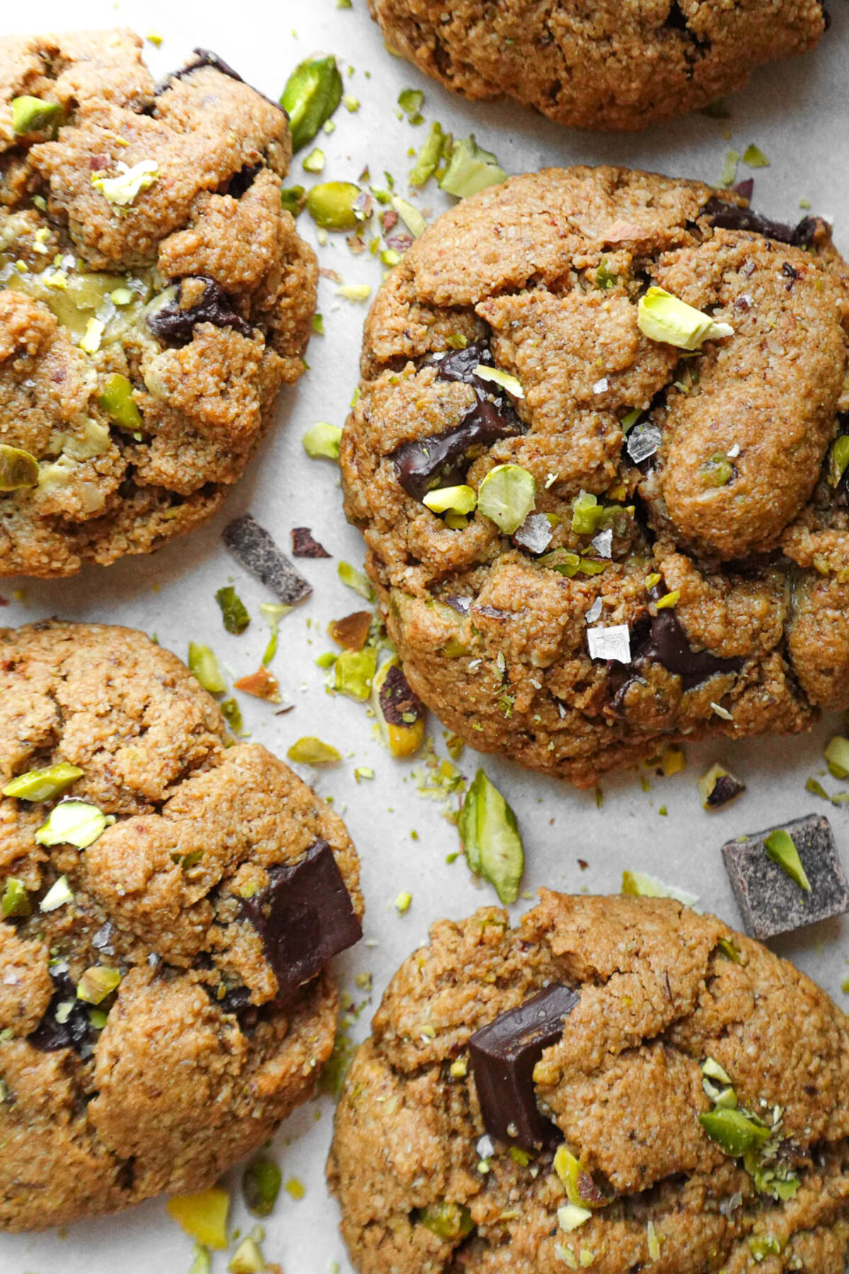 Baked vegan pistachio chocolate chip cookies made with gluten-free flour topped with a sprinkle of flaky sea salt and chopped pistachios