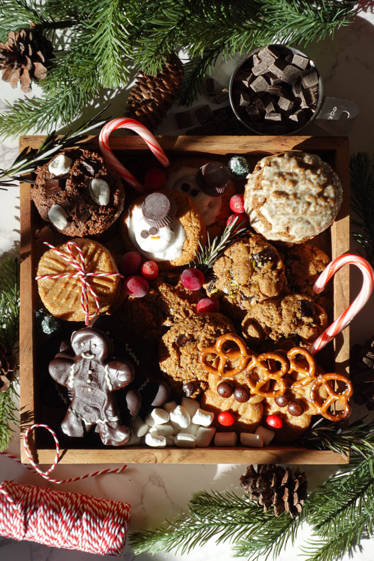 Vegan gluten-free Christmas cookie box with holiday treats, including peanut butter blossoms, chocolate chip cookies, and iced gingerbread cookies