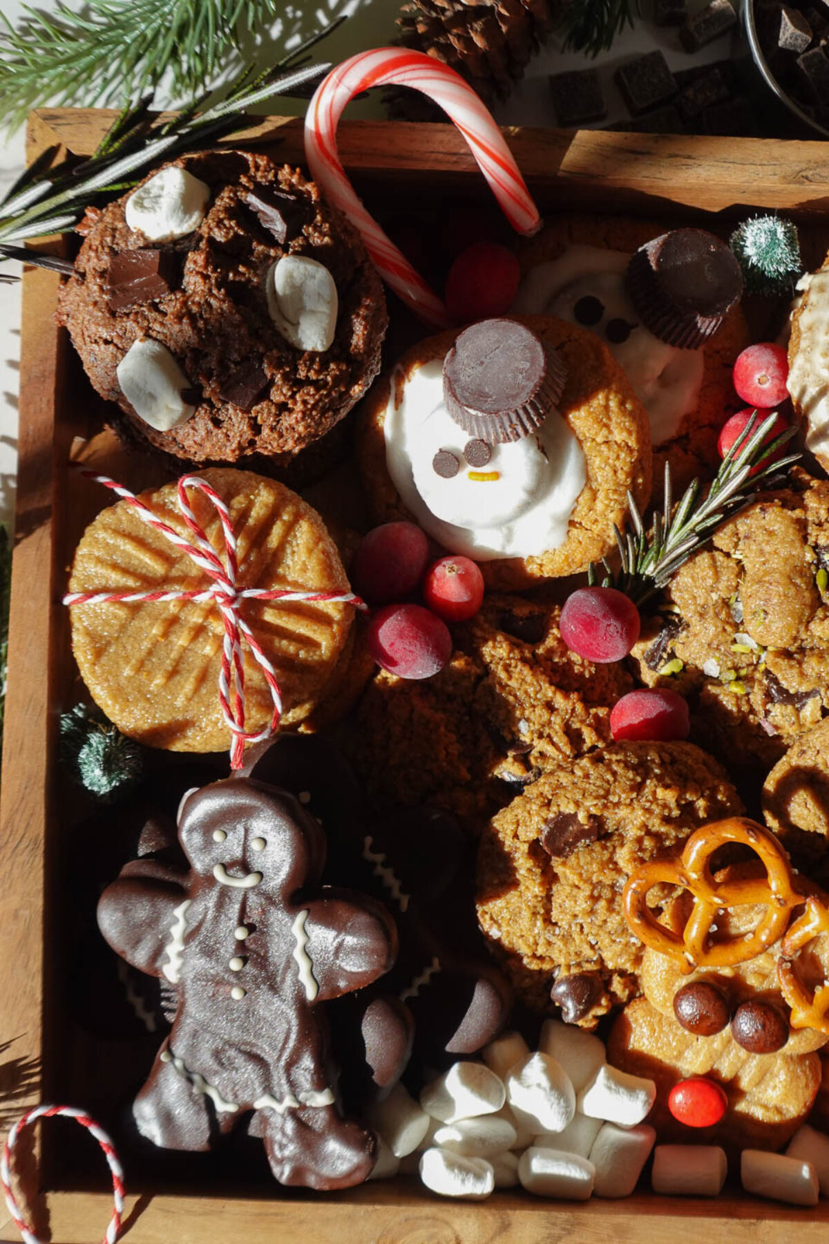 Allergen-friendly Christmas cookie assortment featuring 12 festive vegan and gluten-free holiday cookies decorated with fresh cranberries and rosemary sprigs