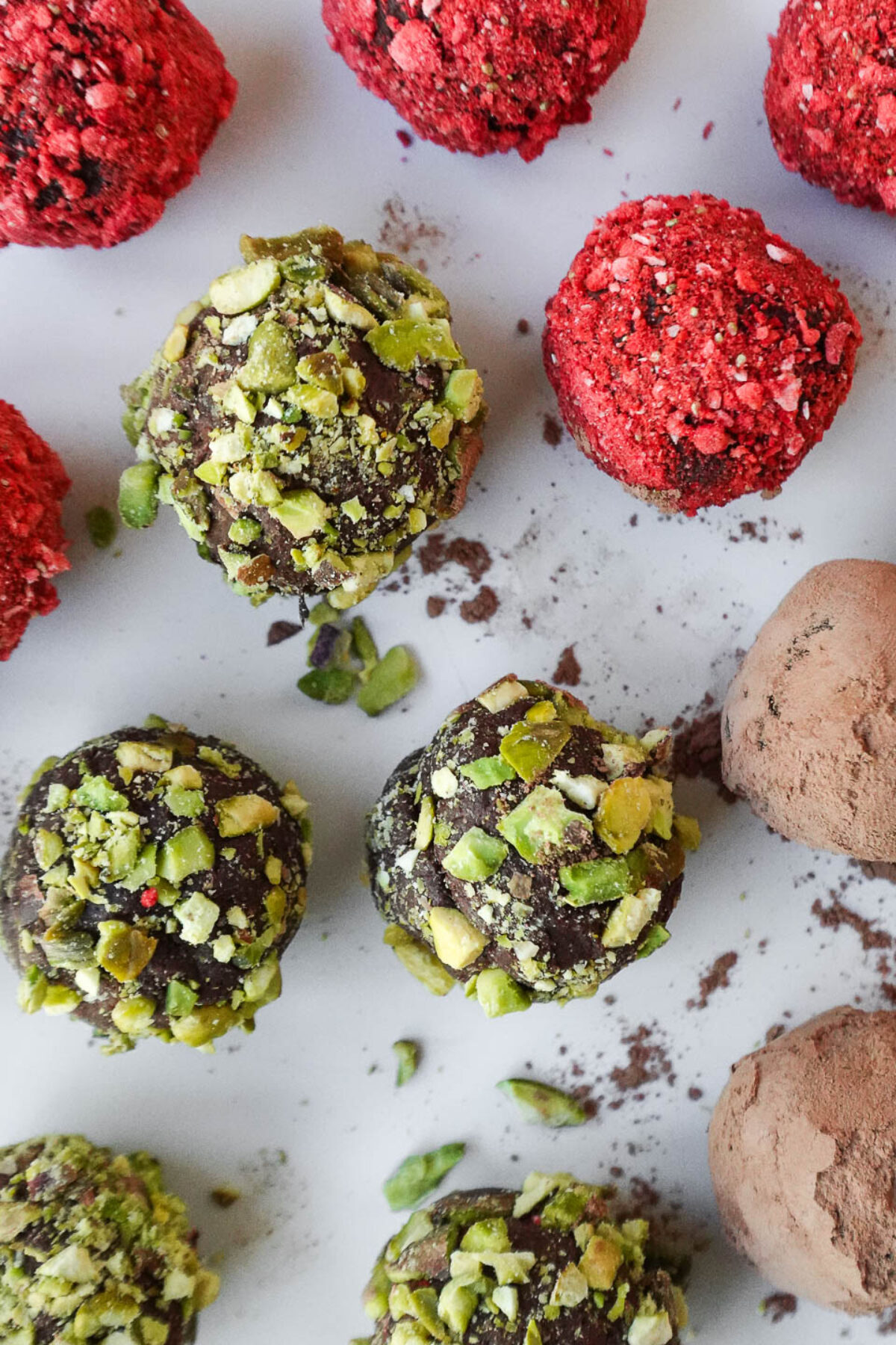 overhead shot of creamy chocolate avocado truffles rolled in cocoa powder, crushed pistachios, and freeze-dried strawberry powder