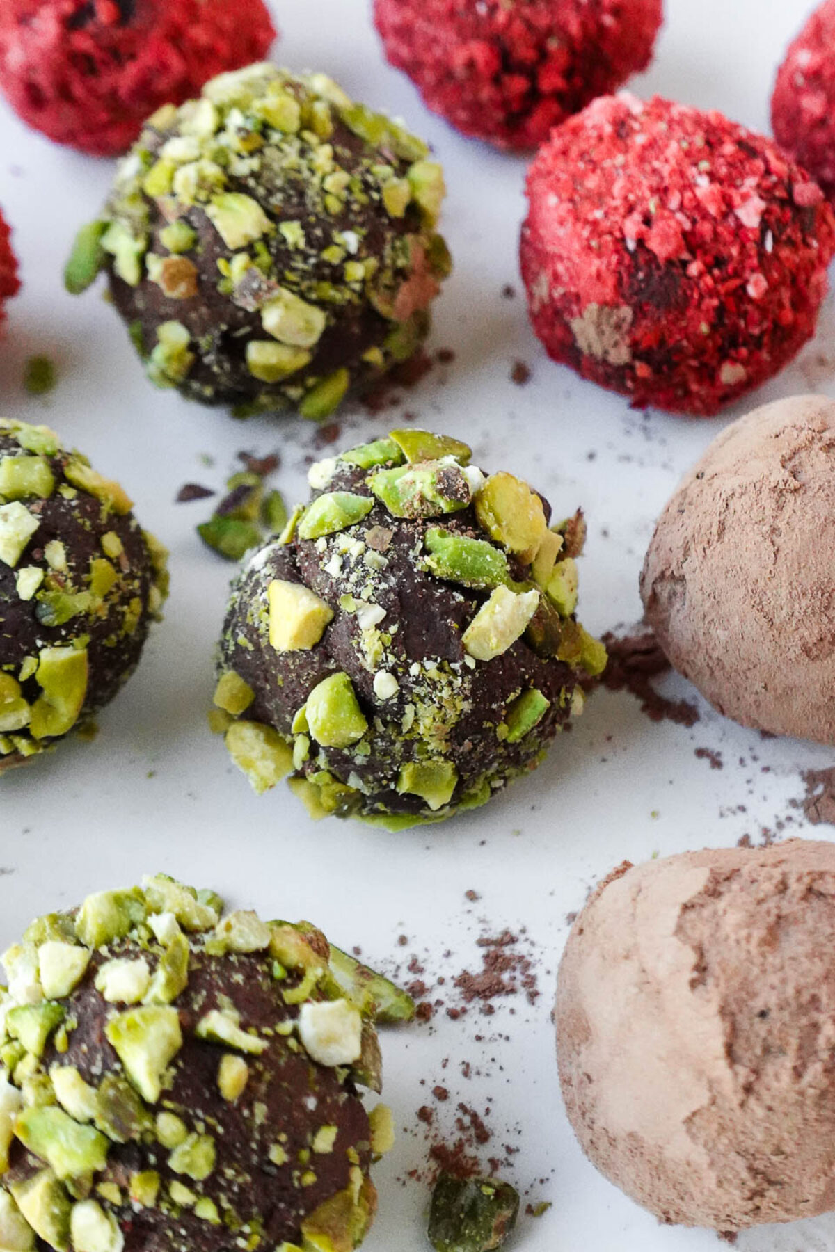 Close-up of creamy chocolate avocado truffles rolled in cocoa powder, crushed pistachios, and freeze-dried strawberry powder